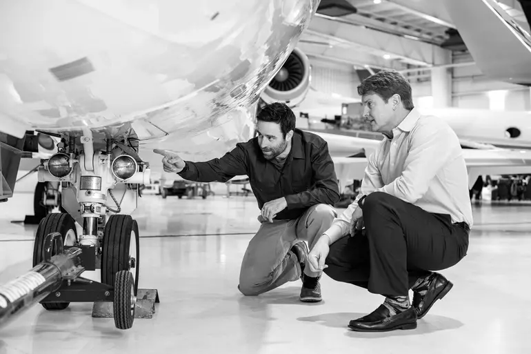 2 asscociates inscpeting an aircraft inside a base